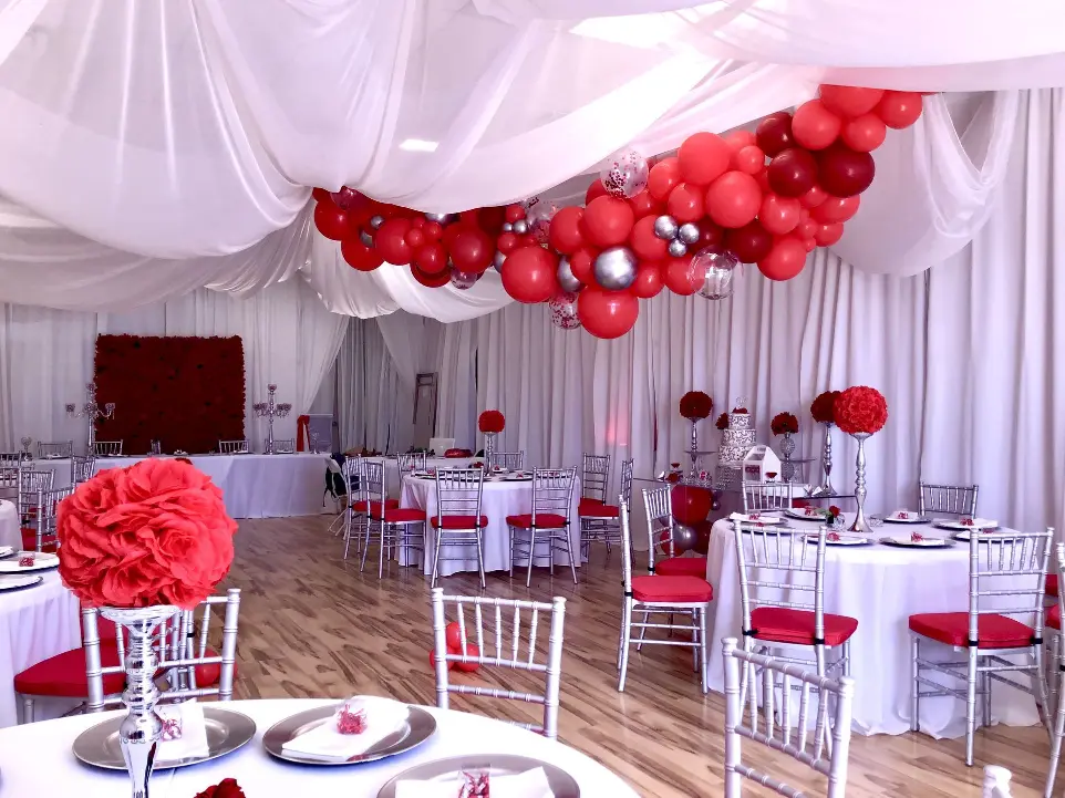 Elegant red and silver balloon ceiling install and guest table setting.