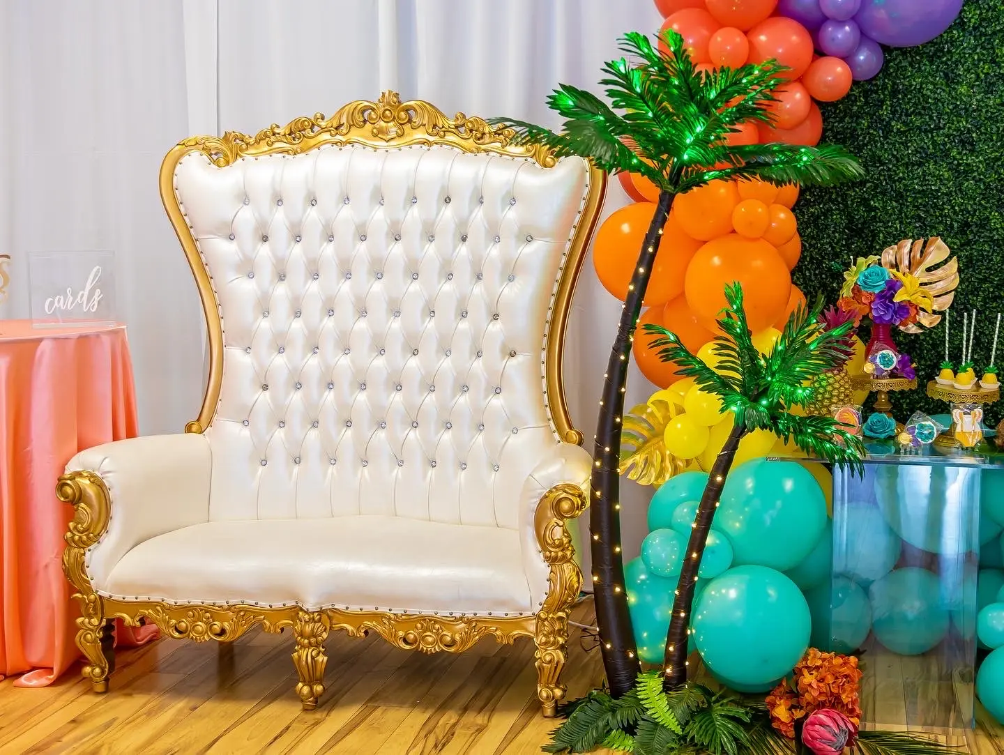 Tropical sunset balloon garland and white and gold throne loveseat