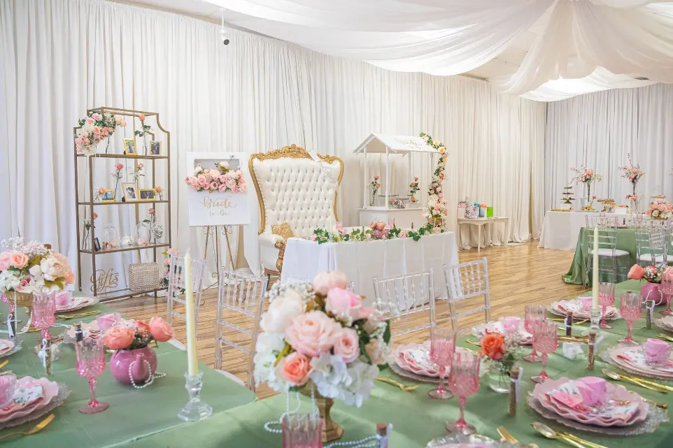 Elegant bridal shower setup at Unique Touch Events in Orlando featuring Chiavari chairs, a white and gold throne loveseat, candy cart, custom table linens, and floral décor rentals.